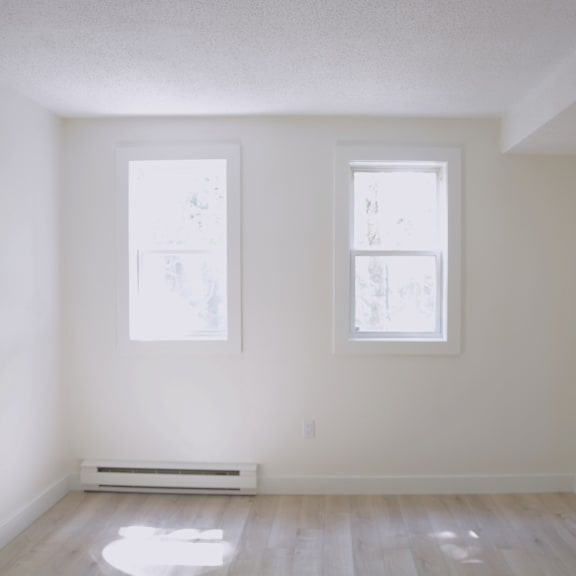 a room with two windows and a radiator on the floor.