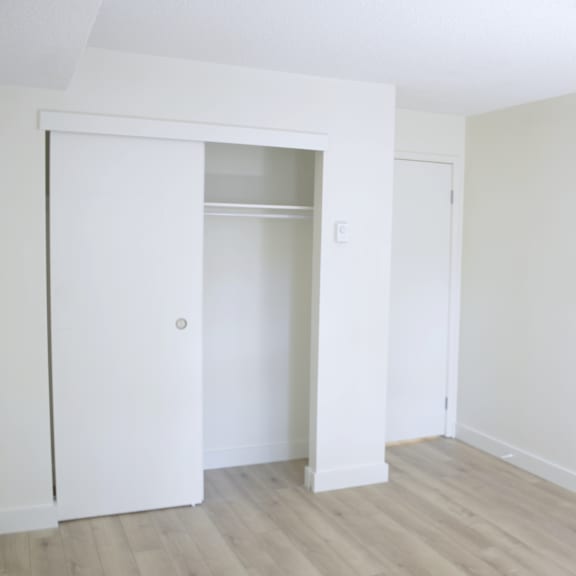 a white door is open to a room with a wooden floor.