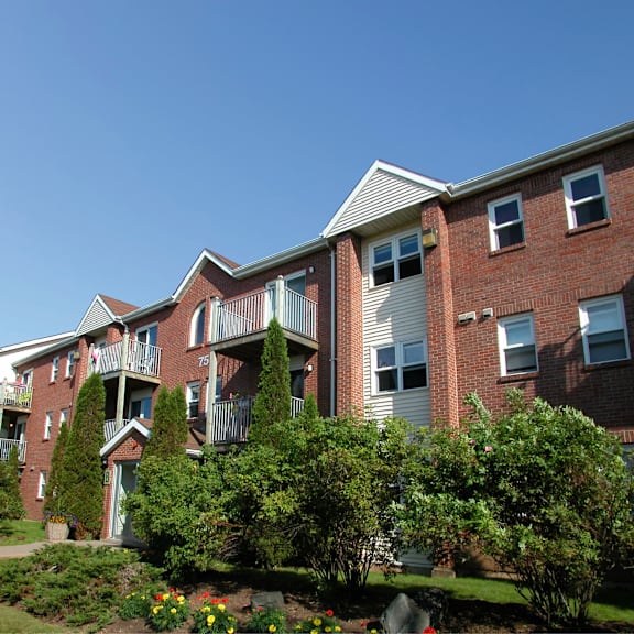 a red brick apartment building with a green lawn in front.