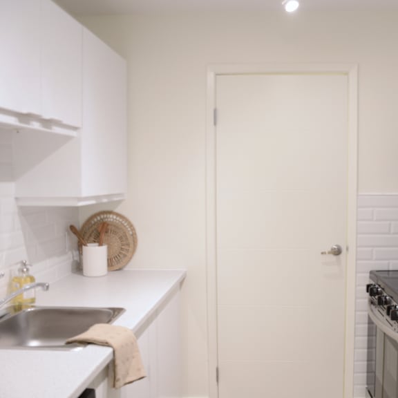 a white kitchen with a sink and a door.