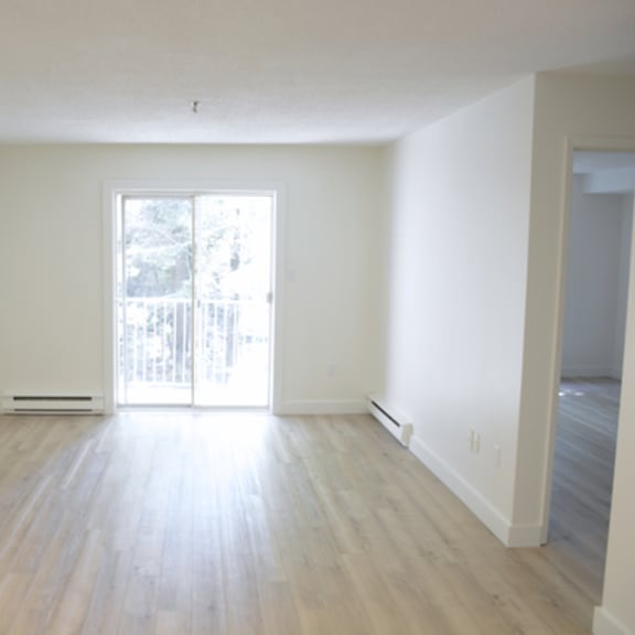 a large empty room with wooden floors and a window.