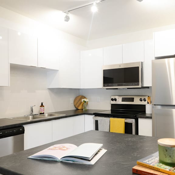 a modern kitchen with a black countertop and stainless steel appliances.