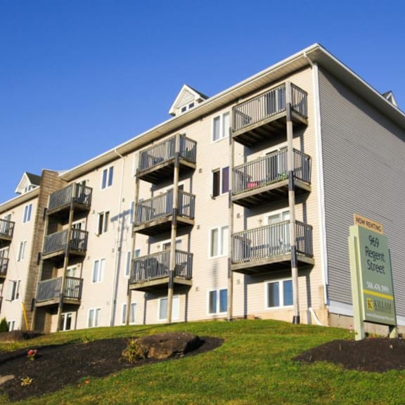 a multi-story apartment building with a sign that reads "sale" in front of it.