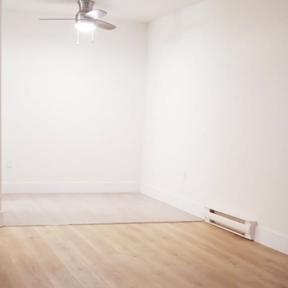 a room with a ceiling fan and wooden flooring.