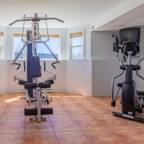 a home gym with a treadmill and a stationary bike.