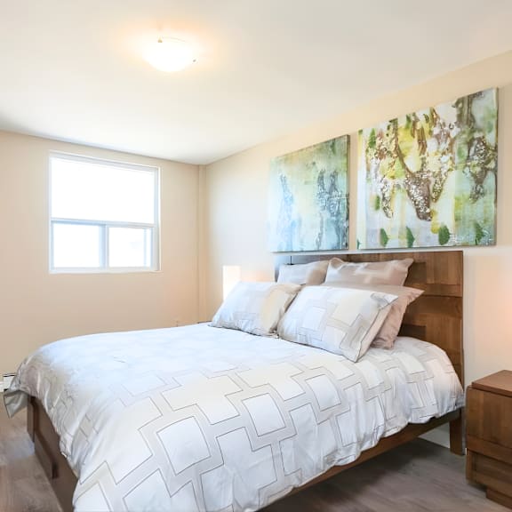 a bedroom with a large bed and two paintings on the wall.