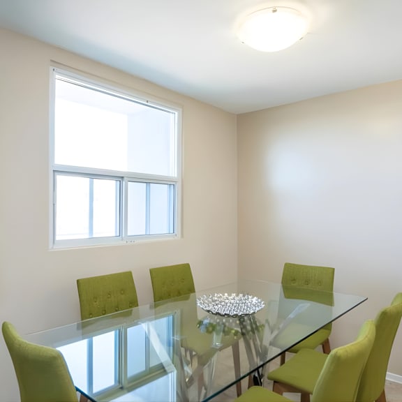 a glass dining table with four chairs and a painting on the wall.