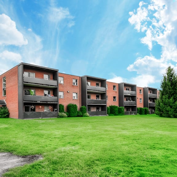a row of red brick apartment buildings with green grass in front.