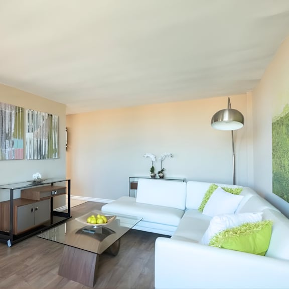 a modern living room with a white couch and a glass coffee table.