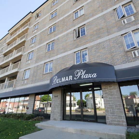 the belmar plaza building is a multi-story brick structure with a black awning.