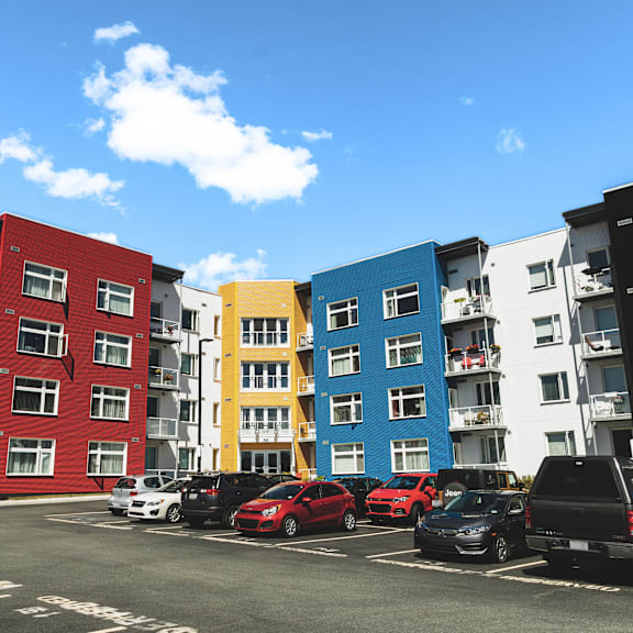 a row of colorful apartment buildings with cars parked in front.
