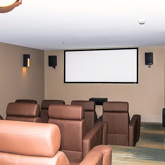 a row of brown leather chairs are arranged in front of a large screen.