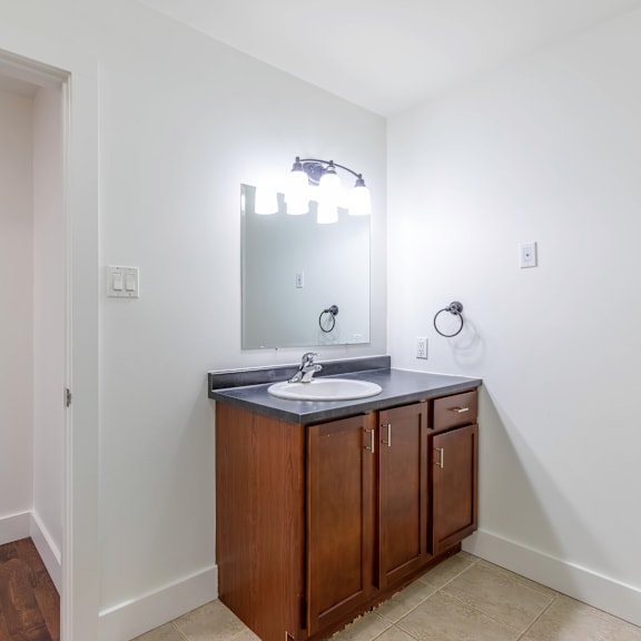 a bathroom with a sink, mirror, and lighting fixture.