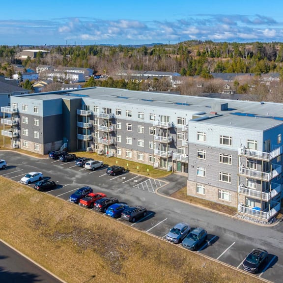 a large apartment complex with a parking lot in front.
