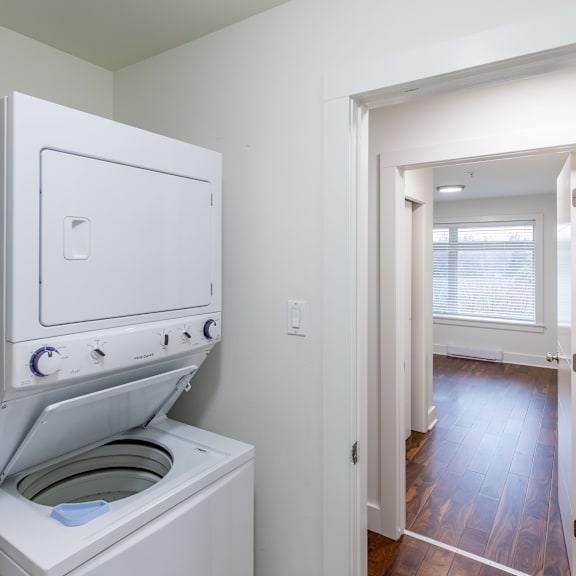 a white oven with a door open is in a room with a wooden floor.