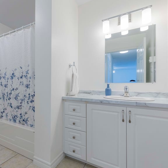 a bathroom with a white shower curtain and a white counter top.