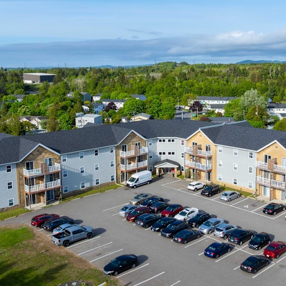 a parking lot with cars and apartment buildings in the background.