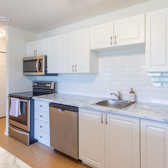 a kitchen with white cabinets and a marble countertop.