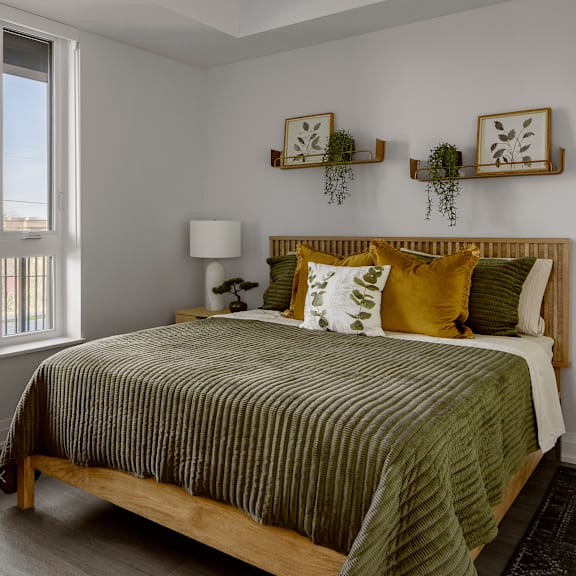 a bedroom with a bed, a lamp, and two wall shelves with plants.