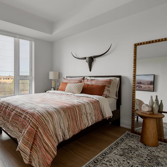 a bedroom with a bed, a mirror, and a rug.