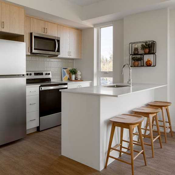 a modern kitchen with a refrigerator, stove, and bar stools.