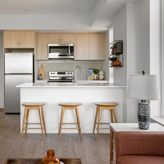 a kitchen with a white countertop and wooden bar stools.