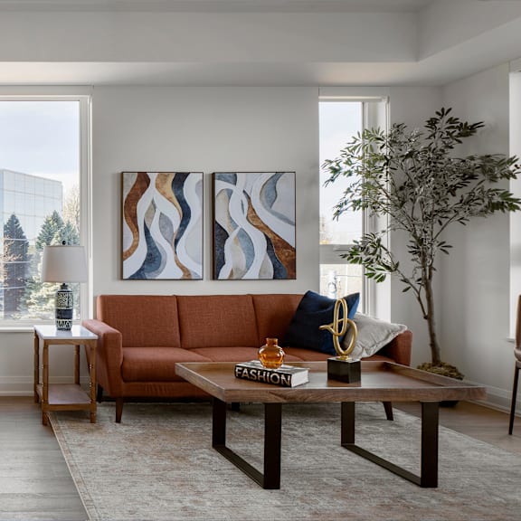 a living room with a brown couch, a coffee table, and a large painting on the wall.
