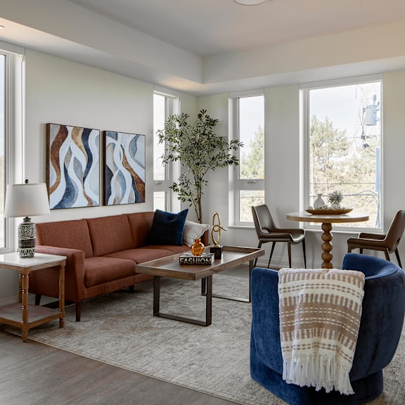a living room with a brown couch, a blue chair, and a painting on the wall.