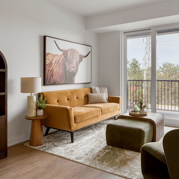 a living room with a tan couch and a large painting of a bull on the wall.