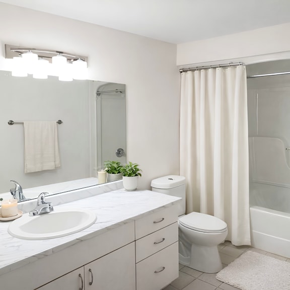 a white bathroom with a sink, toilet, and shower.