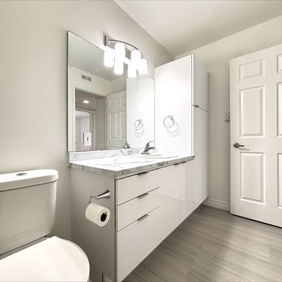 a bathroom with a toilet, sink, mirror, and a door.