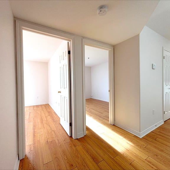 a room with wooden floors and white walls with two open doors.