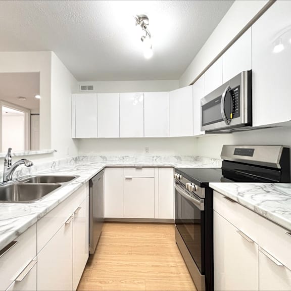 a kitchen with white cabinets and a marble countertop.