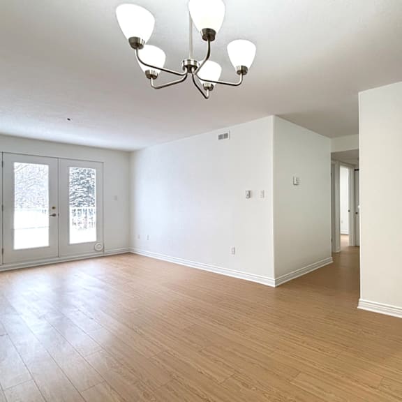 a large empty room with a chandelier and wood flooring.