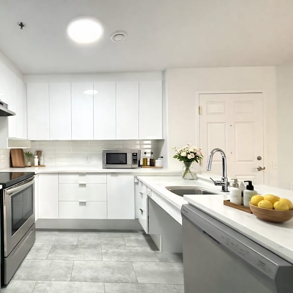 a modern kitchen with white cabinets and stainless steel appliances.