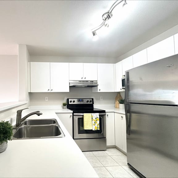 a modern kitchen with stainless steel appliances and white cabinetry.