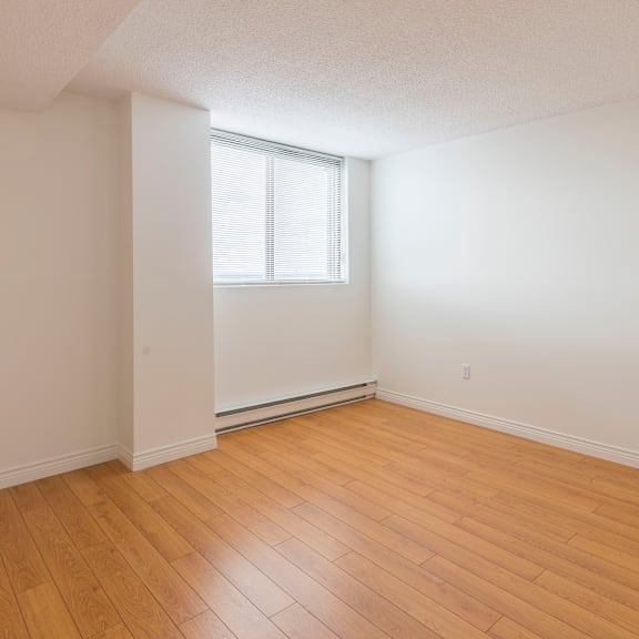 a room with wooden flooring and a window with blinds.