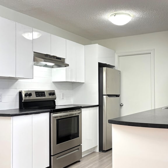a kitchen with white cabinets and a black countertop.