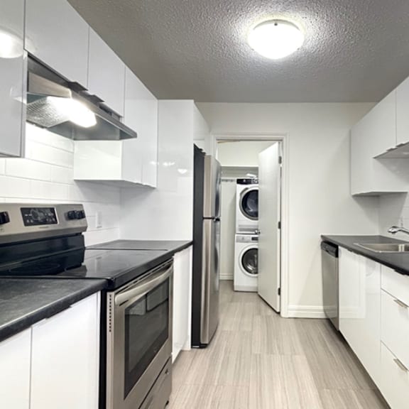 a kitchen with white cabinets and black countertops.