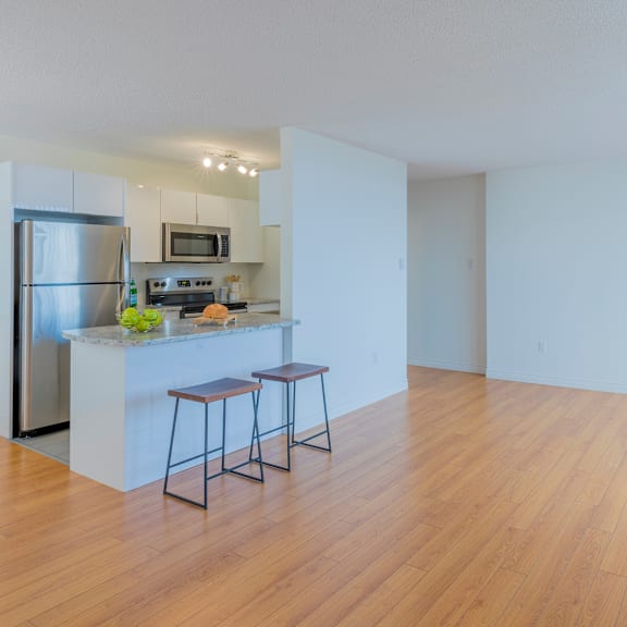 a kitchen with a refrigerator, stove, and bar stools.