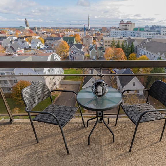 a table with two chairs is set up on a balcony overlooking a town.