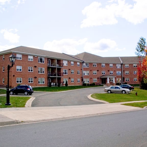 a large red brick building with a parking lot in front.