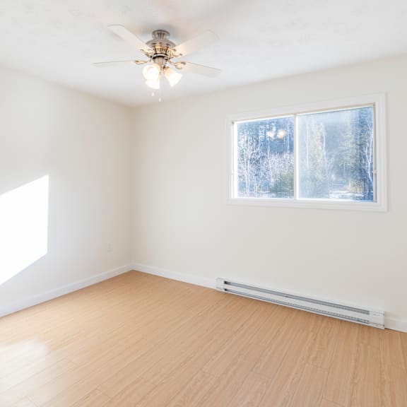 a room with a ceiling fan and a window showing a snowy scene outside.