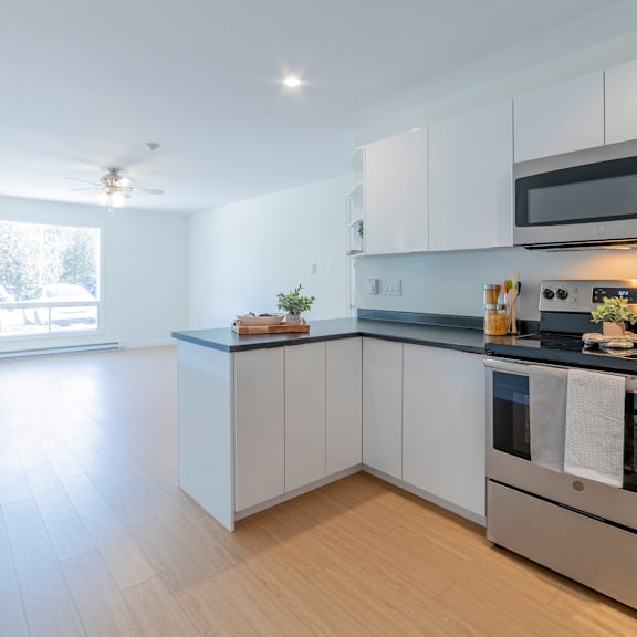 a modern kitchen with white cabinets and a wooden floor.