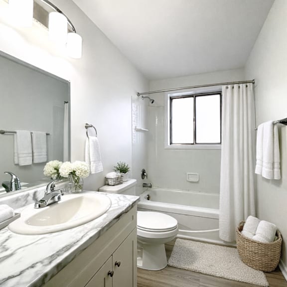 a white bathroom with a marble countertop and a large mirror.