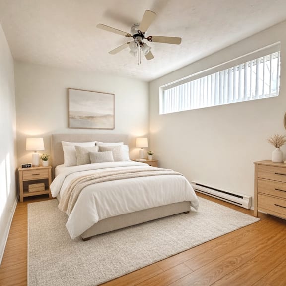 a bedroom with a large bed, a ceiling fan, and a nightstand with a lamp.