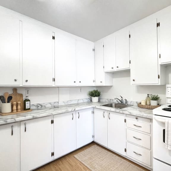 a kitchen with white cabinets and a white stove top oven.