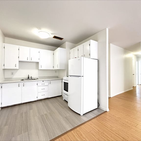 a white kitchen with a white fridge and white cabinets.