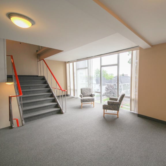 a room with a staircase, chairs, and a window.