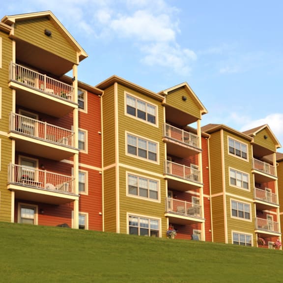 apartment buildings with balconies and windows are lined up on a grassy hill.